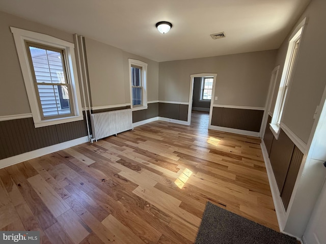 spare room featuring radiator and light hardwood / wood-style floors