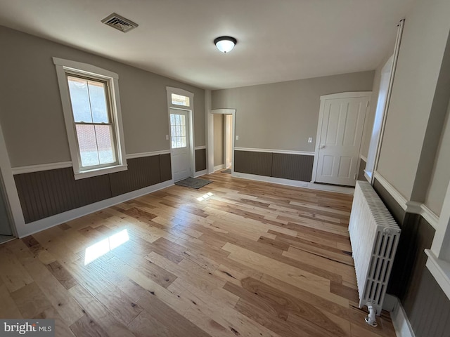 spare room with radiator heating unit and light hardwood / wood-style flooring