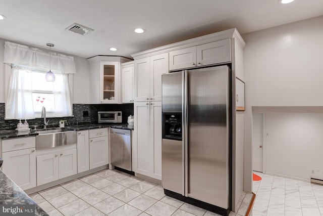 kitchen with sink, white cabinetry, dark stone countertops, appliances with stainless steel finishes, and backsplash