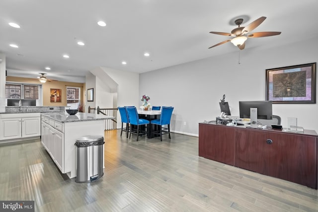 kitchen featuring white cabinetry, light stone countertops, a center island, and light hardwood / wood-style flooring