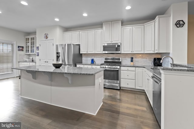 kitchen with a kitchen island, stainless steel appliances, white cabinetry, and a breakfast bar area