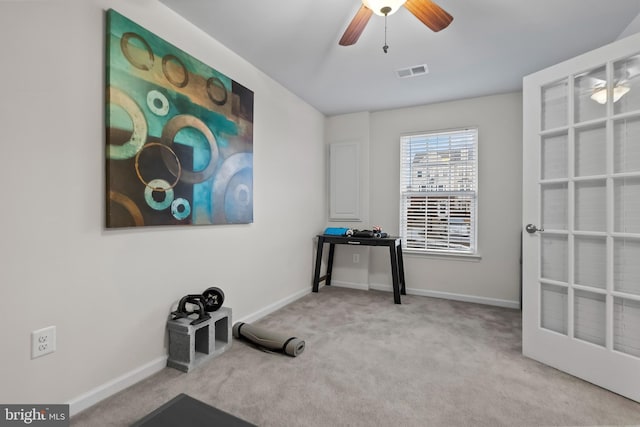 workout room with ceiling fan and light colored carpet