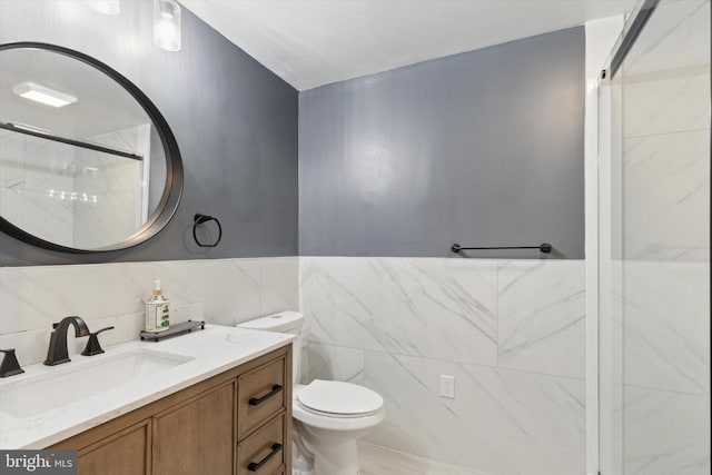 bathroom featuring toilet, tile walls, vanity, and a shower with shower door