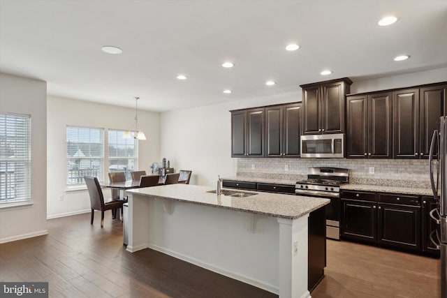 kitchen featuring a breakfast bar, sink, an island with sink, pendant lighting, and stainless steel appliances