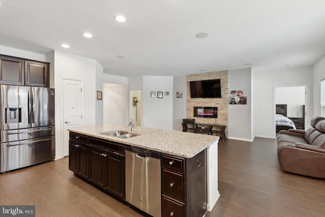 kitchen featuring a kitchen island with sink, sink, stainless steel appliances, and dark brown cabinetry