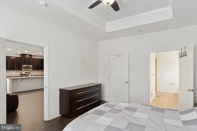 bedroom featuring crown molding, a tray ceiling, hardwood / wood-style flooring, and ensuite bathroom