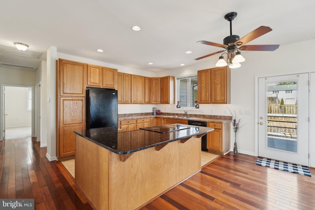 kitchen with recessed lighting, a kitchen island, a kitchen breakfast bar, black appliances, and wood-type flooring