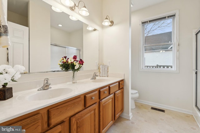 bathroom with double vanity, a shower stall, visible vents, and a sink