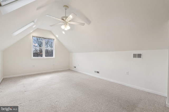 additional living space with a ceiling fan, carpet, visible vents, and lofted ceiling with skylight