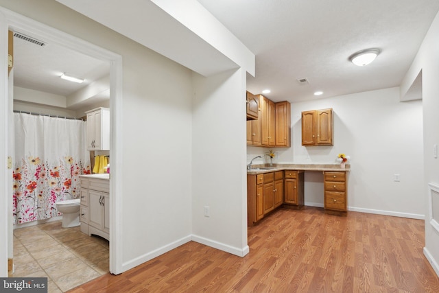 kitchen with light countertops, a sink, visible vents, and light wood-style floors