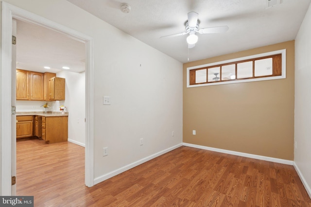 empty room with light wood-style floors, visible vents, baseboards, and a ceiling fan