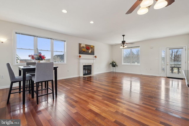 dining room with recessed lighting, wood-type flooring, a fireplace with flush hearth, and baseboards