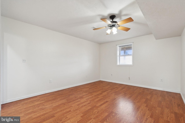 empty room featuring ceiling fan, a textured ceiling, wood finished floors, and baseboards