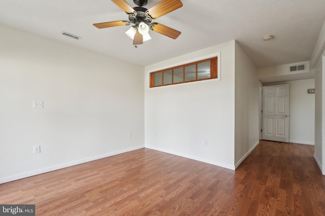 empty room with visible vents, ceiling fan, baseboards, and wood finished floors