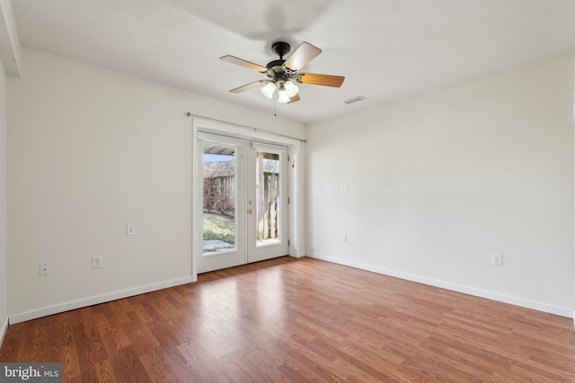 empty room featuring ceiling fan, wood finished floors, visible vents, baseboards, and french doors