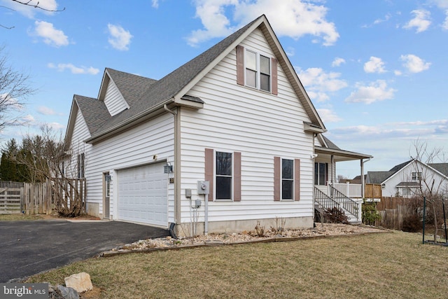 view of side of home featuring aphalt driveway, a porch, a shingled roof, fence, and a yard