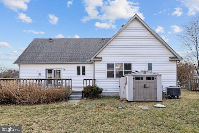 back of property with central air condition unit, an outdoor structure, a yard, a wooden deck, and a storage unit