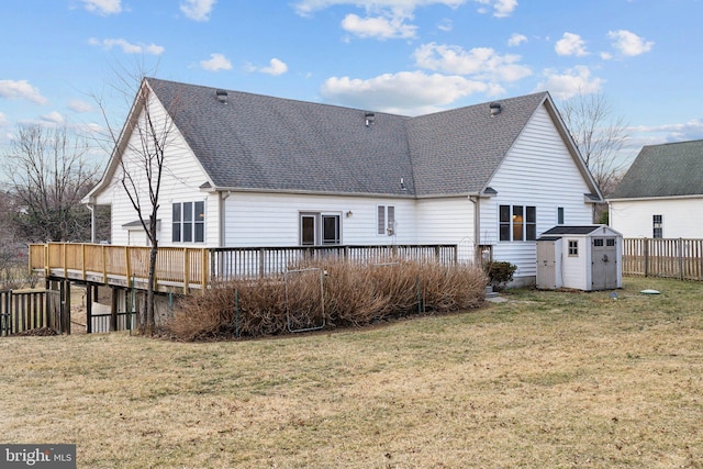 rear view of house with a storage shed, roof with shingles, a yard, a deck, and an outdoor structure