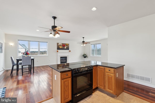 kitchen featuring dark stone counters, electric range, light wood-style flooring, and visible vents