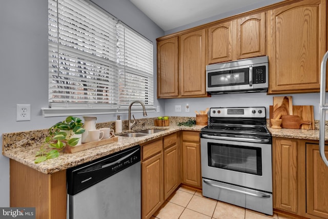 kitchen with light stone counters, stainless steel appliances, light tile patterned flooring, and sink