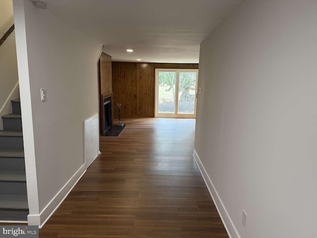 corridor with dark hardwood / wood-style floors and wood walls