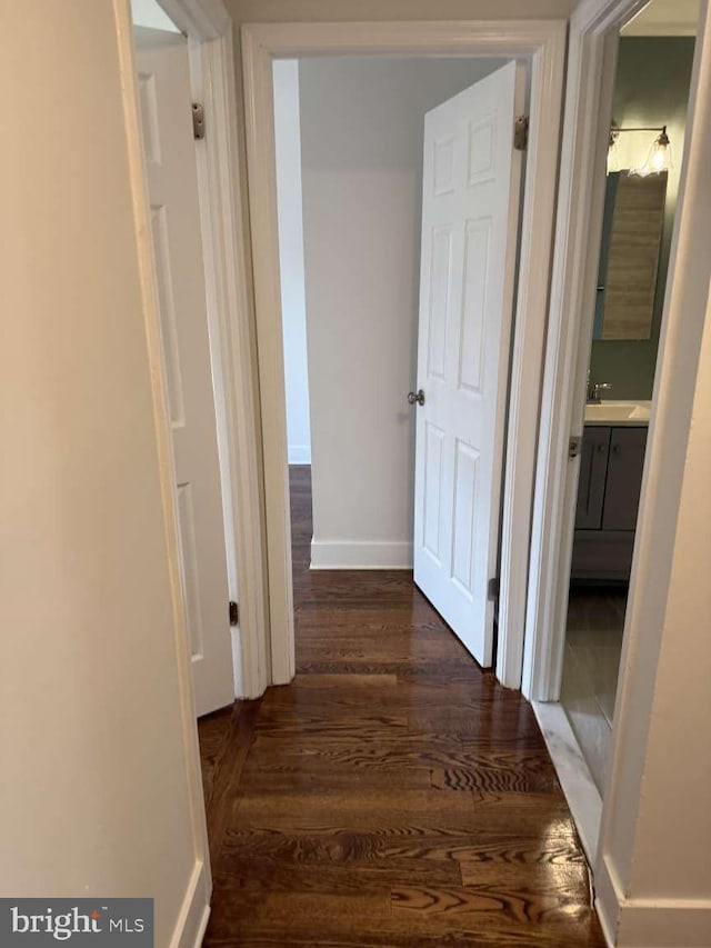 corridor with dark wood-type flooring and sink