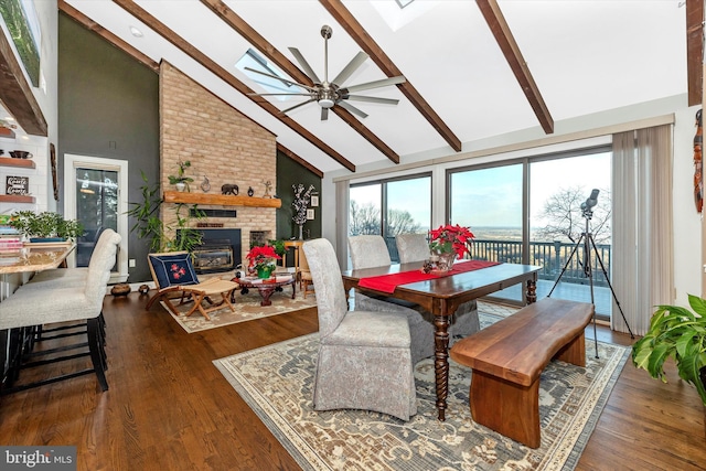 dining area featuring dark hardwood / wood-style flooring, a brick fireplace, a skylight, and ceiling fan