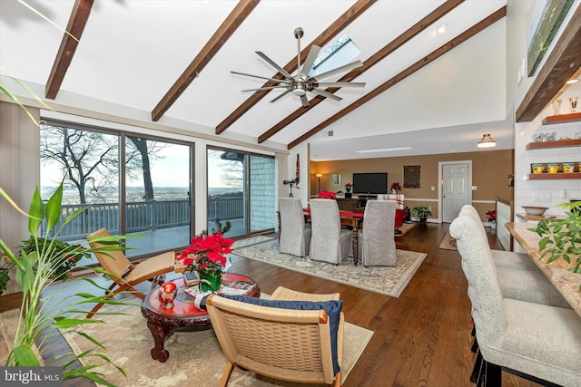 living room featuring ceiling fan, a skylight, high vaulted ceiling, dark hardwood / wood-style floors, and beamed ceiling