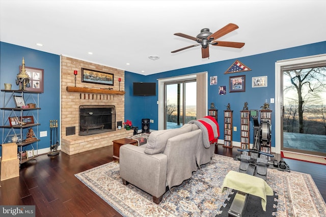 living room featuring ceiling fan, a fireplace, and dark hardwood / wood-style flooring