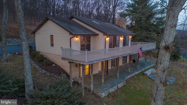 rear view of house featuring a wooden deck and a patio