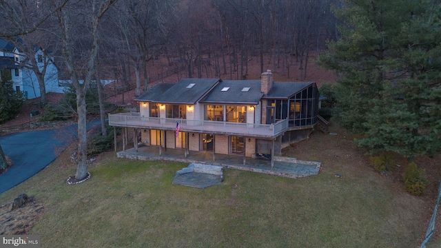 rear view of house featuring a yard, a sunroom, a patio, and a deck