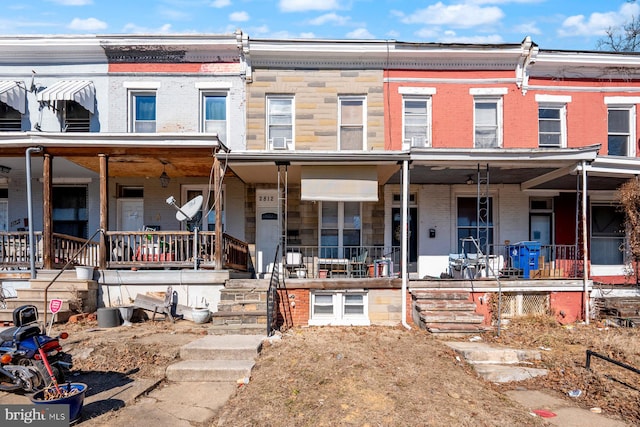 townhome / multi-family property featuring covered porch and brick siding