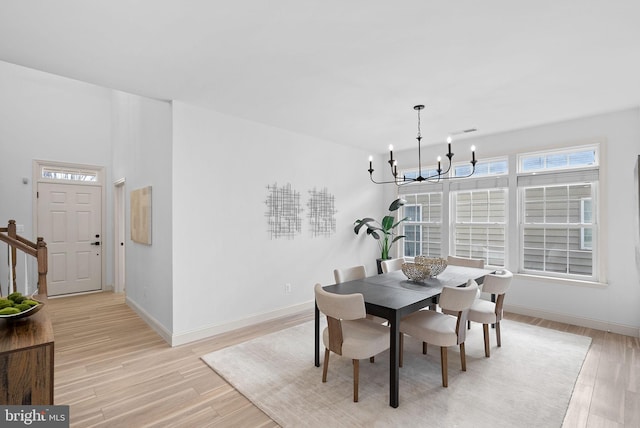 dining space with a chandelier, baseboards, stairs, and light wood-style floors