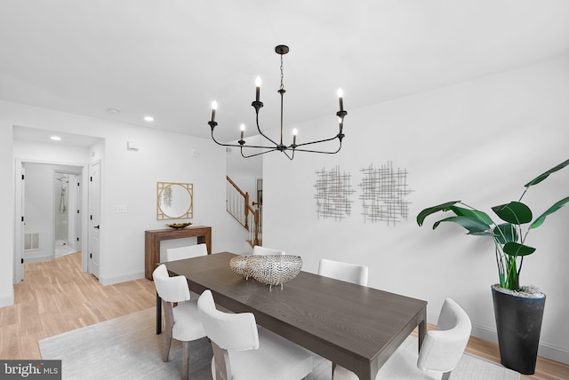 dining room featuring light wood finished floors, visible vents, stairway, and baseboards