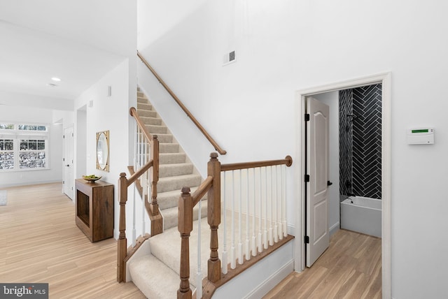 staircase featuring visible vents, baseboards, and wood finished floors