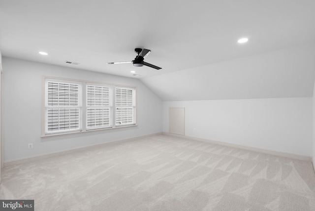 additional living space featuring light carpet, a ceiling fan, visible vents, vaulted ceiling, and baseboards