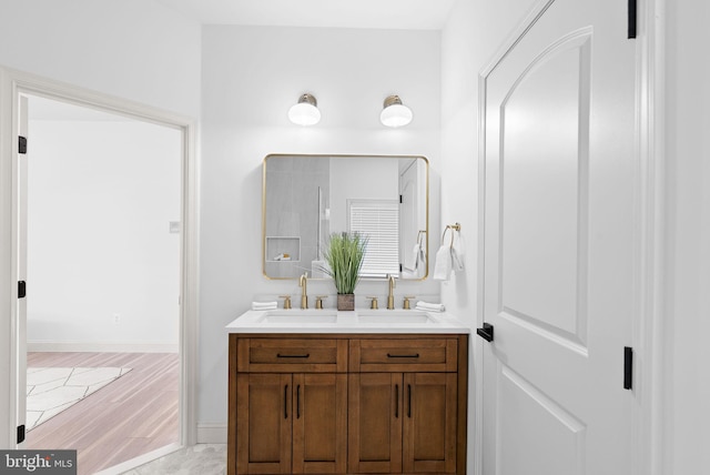 full bath with wood finished floors, a sink, baseboards, and double vanity