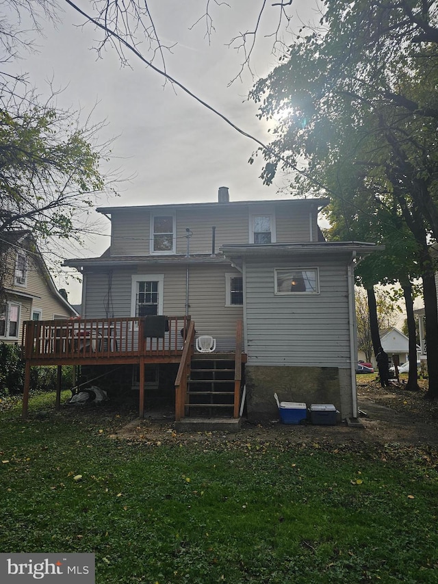 rear view of house with a wooden deck and a lawn