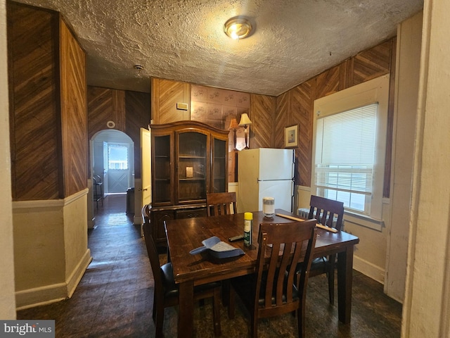 dining room with a wealth of natural light, a textured ceiling, and wooden walls