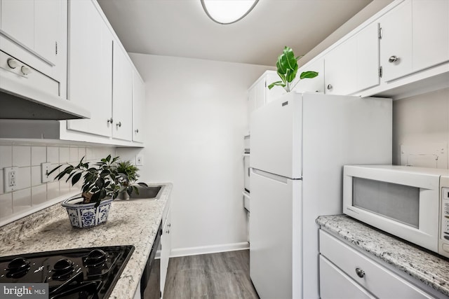 kitchen with white appliances, light hardwood / wood-style floors, decorative backsplash, and white cabinets