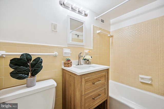 full bathroom featuring vanity, tiled shower / bath combo, tile walls, and toilet