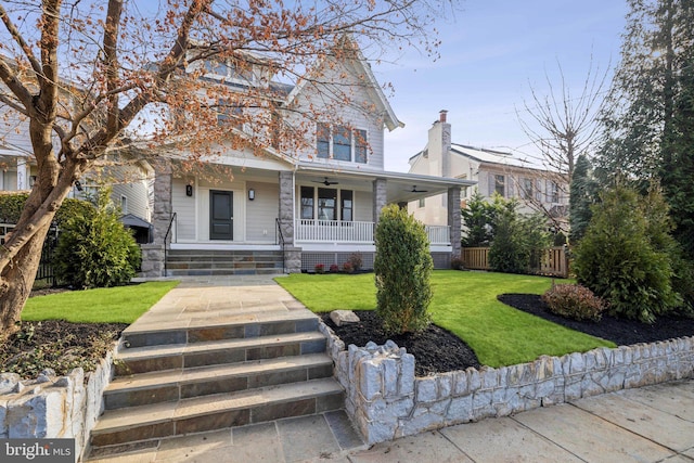 view of front of home featuring ceiling fan, a front yard, and covered porch