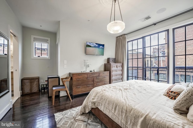 bedroom with multiple windows and dark wood-type flooring