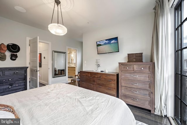 bedroom with connected bathroom and dark hardwood / wood-style flooring