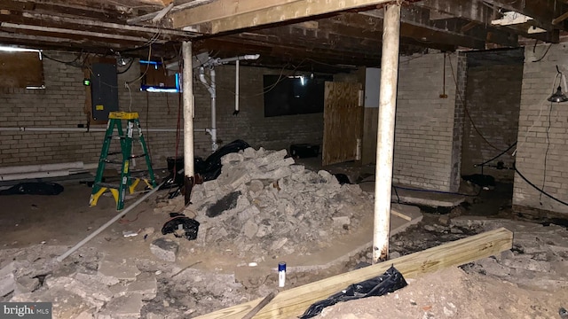 basement featuring brick wall and electric panel