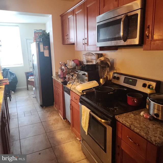 kitchen featuring light tile patterned flooring, appliances with stainless steel finishes, and light stone countertops