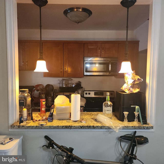 kitchen with light stone countertops, appliances with stainless steel finishes, and decorative light fixtures