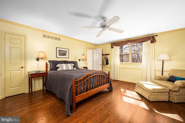 bedroom featuring baseboards, wood finished floors, visible vents, and crown molding