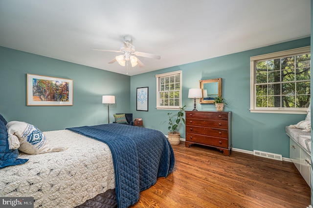 bedroom featuring visible vents, ceiling fan, baseboards, and wood finished floors