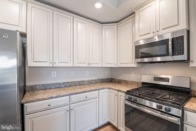 kitchen featuring appliances with stainless steel finishes, light stone countertops, and white cabinets